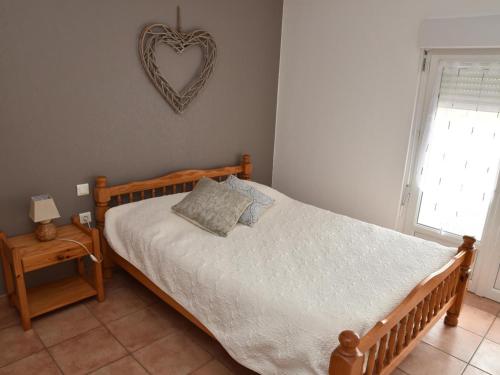 a bedroom with a bed and a heart plaque on the wall at Gîte indépendant avec piscine, grande terrasse, jardin, barbecue, proche St Pourçain/Sioule et Souvigny - FR-1-489-78 in Cressanges