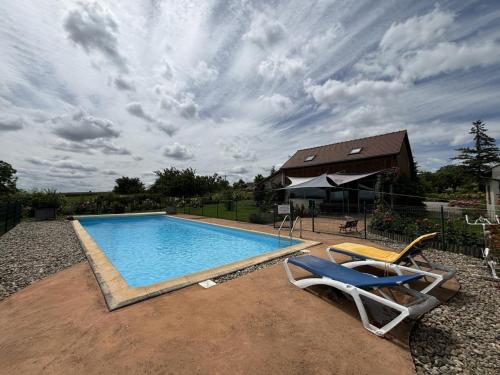 - une piscine avec 2 chaises longues et une maison dans l'établissement Gîte avec piscine et roseraie près de Vichy - FR-1-489-545, à Louchy-Montfand