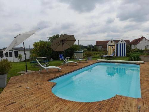 une piscine avec des chaises et un parasol dans l'établissement Gîte Contemporain pour 4 avec Piscine Chauffée et Bureau à Proximité des Sites Historiques - FR-1-489-444, à Louchy-Montfand