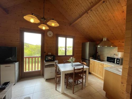 une cuisine avec une table et des chaises dans une pièce dans l'établissement Chalet avec Clim, Wi-Fi et Animaux Acceptés à Saint-Bonnet-Tronçais - FR-1-489-445, à Saint-Bonnet-Tronçais