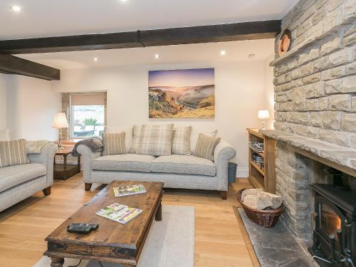 a living room with couches and a stone fireplace at Manor Cottage in Tideswell