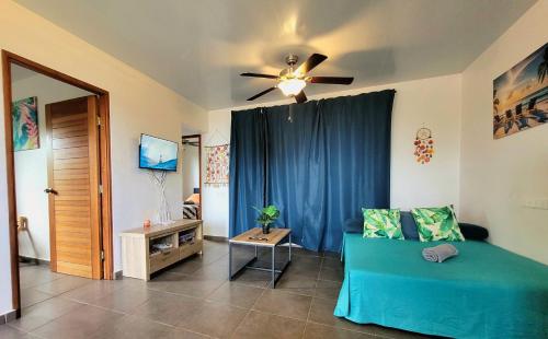 a living room with a blue couch and a ceiling fan at Teahupo'o Lodge Tahiti - Fare Terre et Mer - climatisé - canoe et paddle in Teahupoo