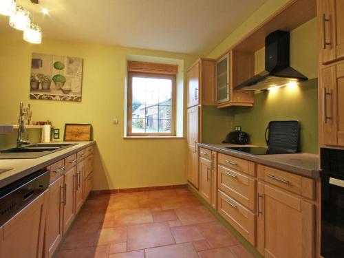 a large kitchen with wooden cabinets and a window at Maison écologique du XVe siècle avec jardin clos et garage, idéale pour une escapade paisible - FR-1-497-7 in La Baroche-sous-Lucé
