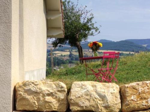 a red table with flowers on it next to a building at Gîte rénové avec fibre et confort à Panissières - FR-1-496-367 in Panissières