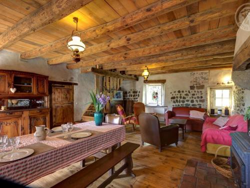 un salon avec une table et un canapé dans l'établissement Gîte cosy avec jardin, terrasse ombragée, poêle à bois, et équipements bébé à Saint-Georges-Haute-Ville - FR-1-496-191, à Saint-Georges-Haute-Ville