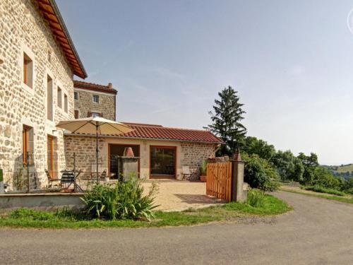 an external view of a house with an umbrella at Gîte spacieux avec terrasse en forêt, 12 lits, proche randonnées - FR-1-496-314 in Verrières-en-Forez