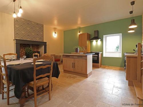 une cuisine et une salle à manger avec une table et une cuisine, ainsi qu'une table et des chaises dans l'établissement Maison de charme avec jardin clos, proche de Sées et activités, animaux bienvenus - FR-1-497-150, à Aunou-sur-Orne