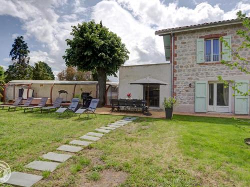 a house with chairs and a table in the yard at Gîte de charme avec spa, sauna et jardin privatif à Montbrison - FR-1-496-309 in Montbrison