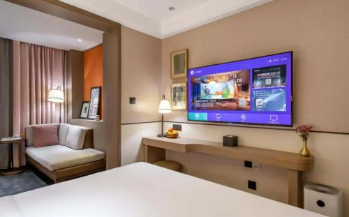 a hotel room with a bed and a flat screen tv at Manxin Hotel - Beijing Zhongguancun University of Technology in Beijing