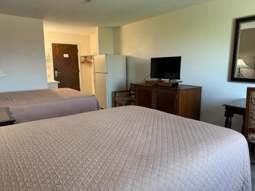 a hotel room with two beds and a refrigerator at Island Inn in Grand Island
