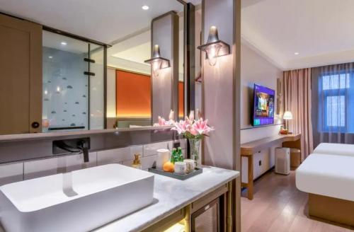 a bathroom with a sink and a large mirror at Manxin Hotel - Beijing Zhongguancun University of Technology in Beijing