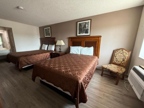 a hotel room with two beds and a chair at Island Inn in Grand Island