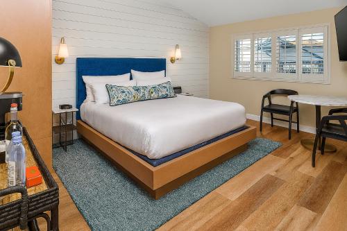 a bedroom with a bed with a blue headboard and a table at Inn At Rose's Landing in Morro Bay