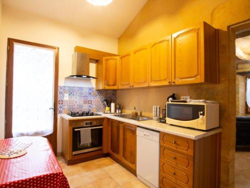 une petite cuisine avec des armoires jaunes et un four micro-ondes dans l'établissement Maison isolée avec jardin à 1 km du centre de Sarlat, idéal pour visites et activités de plein air - FR-1-616-340, à Sarlat-la-Canéda