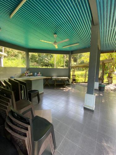 a patio with a blue roof and a table and chairs at BESTUBA COTTAGE at PULAU TUBA, LANGKAWI in Pulau Selang Besar
