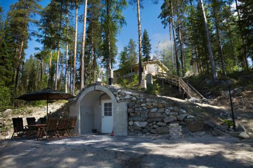 a building with a stone wall and a table and chairs at Lake Cottage Jänisvaara in Kolinkylä