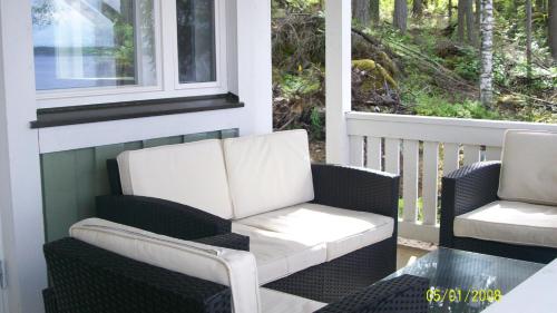a porch with two chairs and a table and a window at Lake Cottage Jänisvaara in Kolinkylä