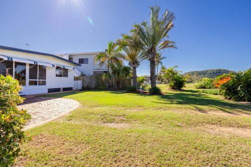 a yard with palm trees and a house at Family Tides in Kinka