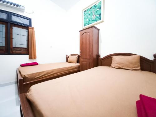 two beds in a room with a window at Wisma Trubus Syariah RedPartner Near RSUD Koesma Tuban in Tuban