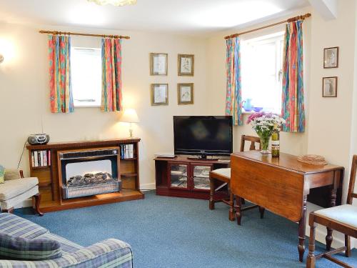 a living room with a fireplace and a tv at Pig Sty Cottage - E1867 in Powerstock