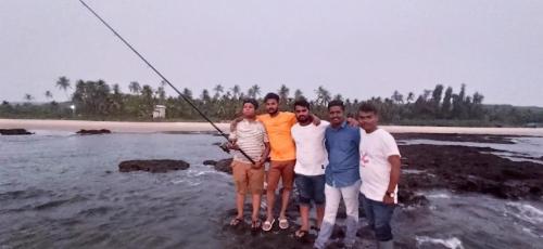 a group of people standing in the water fishing at Samant Beach Resort in Malvan