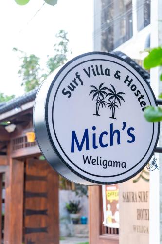 a sign for a restaurant with two palm trees at Mich's Surf Villa & Hostel in Weligama