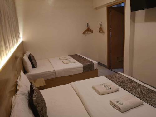 a bedroom with two beds and a door to another room at Bamboo Garden Bussiness Inn in Dipolog