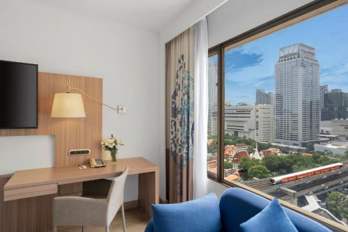 a hotel room with a desk and a large window at Novotel Bangkok on Siam Square in Bangkok
