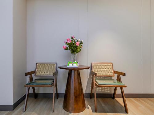 two chairs and a table with a vase of flowers at 重庆莎霏酒店大渡口店 in Chongqing