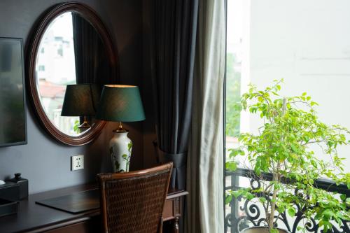 a lamp sitting on a desk next to a window at La Sinfonía Majesty Hotel and Spa in Hanoi