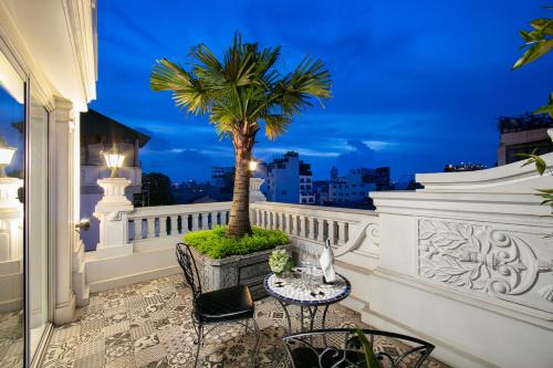a balcony with a table and a palm tree on it at La Sinfonía Majesty Hotel and Spa in Hanoi