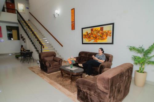 a woman sitting on a couch in a living room at Hotel Estancia Real in Piura