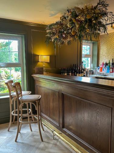 a bar with two stools and a counter with wine bottles at Tŷ Afon - River House in Beddgelert