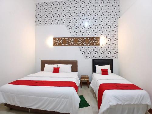 a bedroom with two beds with red and white sheets at RedDoorz at Ndalem Eyyang Syariah Stasiun Klaten in Klaten
