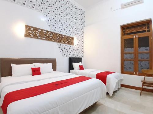 a bedroom with two beds and a window at RedDoorz at Ndalem Eyyang Syariah Stasiun Klaten in Klaten