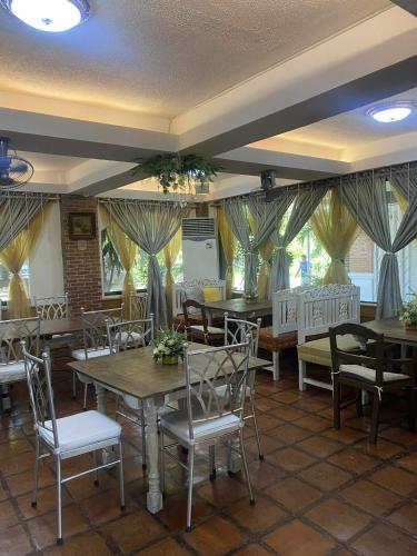 a dining room with tables and chairs and windows at The Palacio de Laoag in Laoag