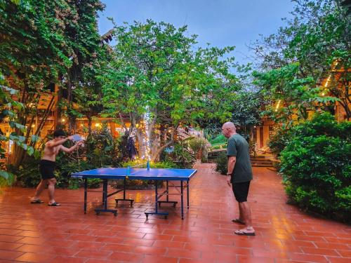 two men standing around a ping pong table in front of a fountain at Trang An Village Homestay in Ninh Binh