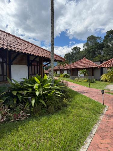 a house with a garden and a brick walkway at El Tesoro - Finca Hotel Eje Cafetero in Calarcá