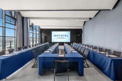 a conference room with blue tables and chairs and a screen at Novotel Kunming City Center in Kunming