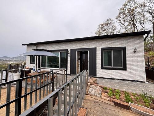 a small house with a deck with an umbrella at House of Rising Sun - Nanhee House in Incheon