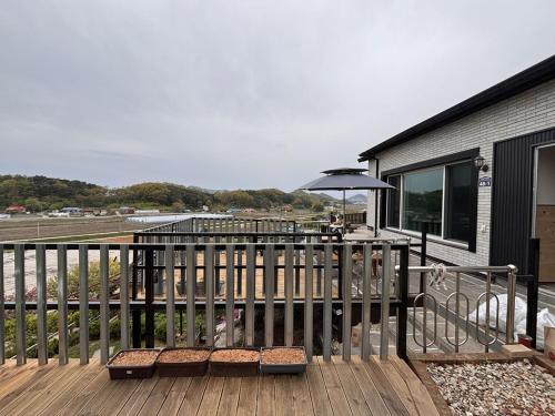 a deck with a table and an umbrella at House of Rising Sun - Nanhee House in Incheon