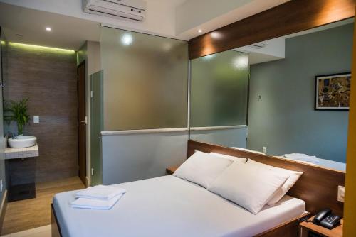 a bedroom with a bed with a mirror and a bathroom at Ouro Motel in Sepetiba