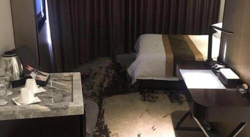 a hotel room with a bed and a desk at Harbin Splendent Hotel in Harbin