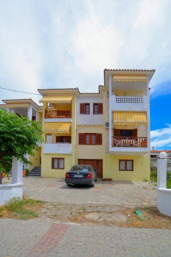 a yellow building with a car parked in front of it at Agapitos Apartments in Nikiti