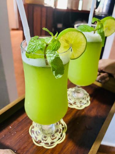 two green cocktails with lime and mint on a table at The Curry Lodge - Thimbiriya in Habaraduwa