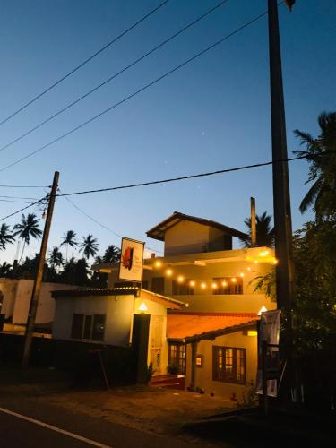 a building with lights on the side of a street at The Curry Lodge - Thimbiriya in Habaraduwa