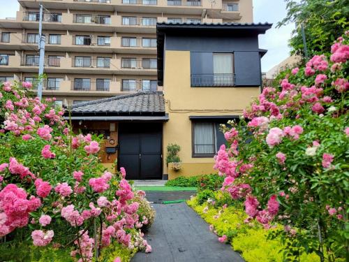 a house with pink flowers in front of a building at 古民家　日乃家～HINOYA　８名まで滞在可能 in Funabashi