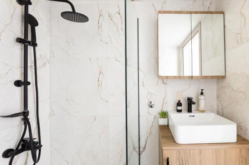 a bathroom with a shower with a sink and a mirror at AEONS - Hotelia Hospitality Group in Thessaloniki