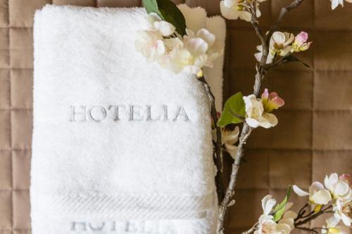 a towel with the word hotelaho next to flowers at AEONS - Hotelia Hospitality Group in Thessaloniki