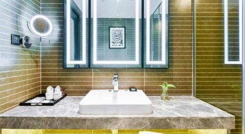 a bathroom with a sink and a mirror at Xana Hotelle Wuxi Railway Station Zhongshan Road in Wuxi